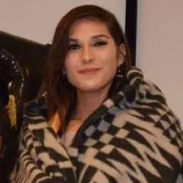 Fawn Weaver smiles at the camera while wrapped in a black and white blanket in front of a white wall.