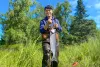 Torin Jacobs II poses in waders with a large fish, likely a Chinook salmon, on a sunny day in Alaska.